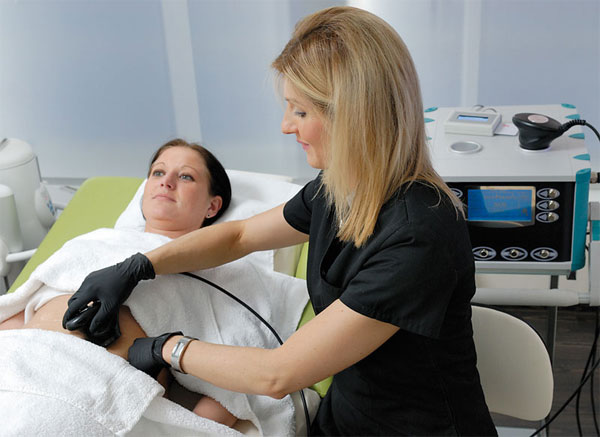 Eine Ärztin führt eine Ultraschall-Lipolyse Behandlung bei einer Patientin durch